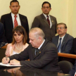 El ministro Luis María Benítez Riera firma el documento, mientras obserba la presidenta de la Circunscripción, Mara Ladan. Acompaña el gobernador de Itapúa Luis Gneiting.